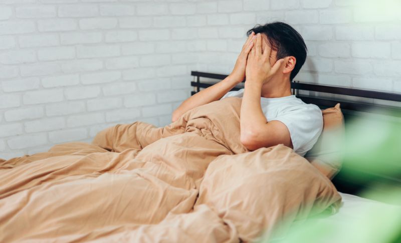 ベッドで頭を抱える男性